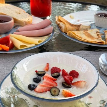 Morning outdoor breakfast with fresh berries, bread, cheese, and crepes.