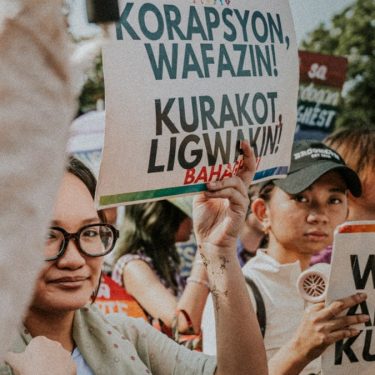 People holding protest signs at a rally.
