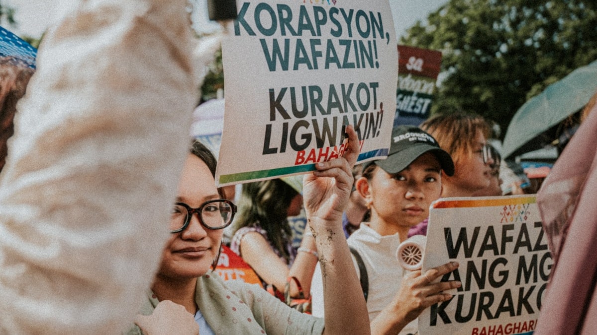 People holding protest signs at a rally.